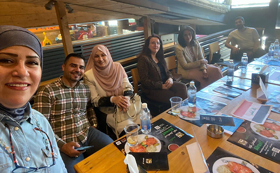 Six members of the Newcastle University Iraq Alumni Network smiling at the camera whilst sitting at a table in a restaurant. 